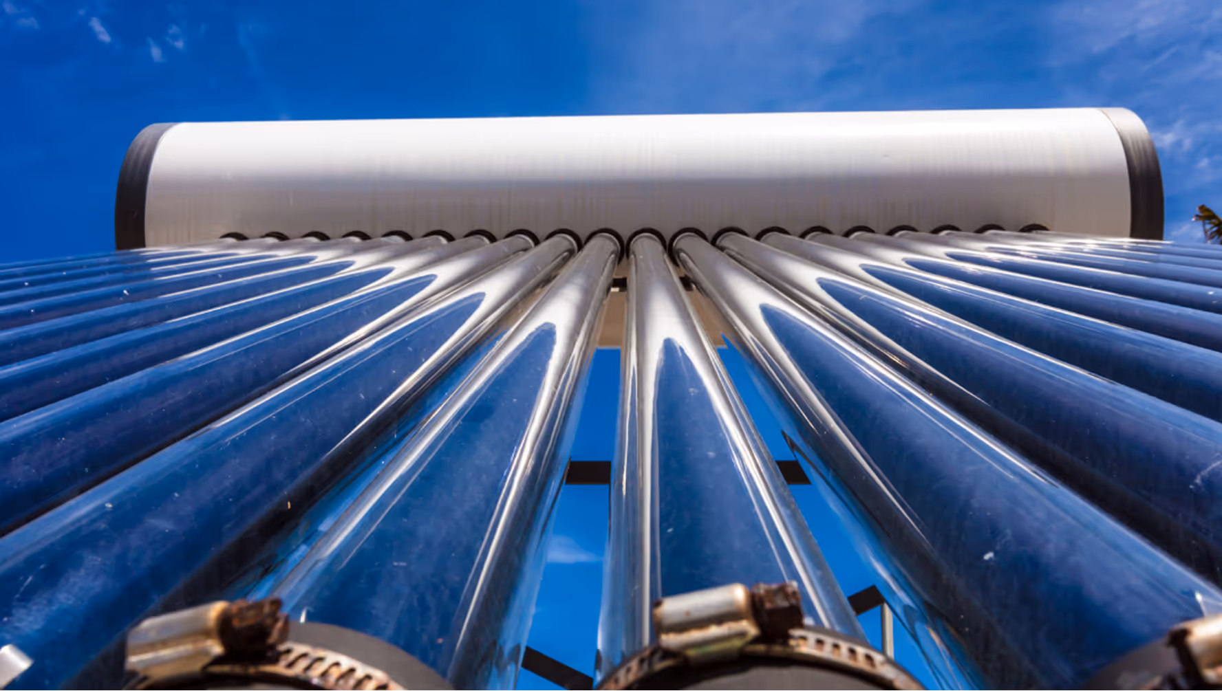 Blick von unten auf reflektierende Solarröhren mit blauem Himmel im Hintergrund.
