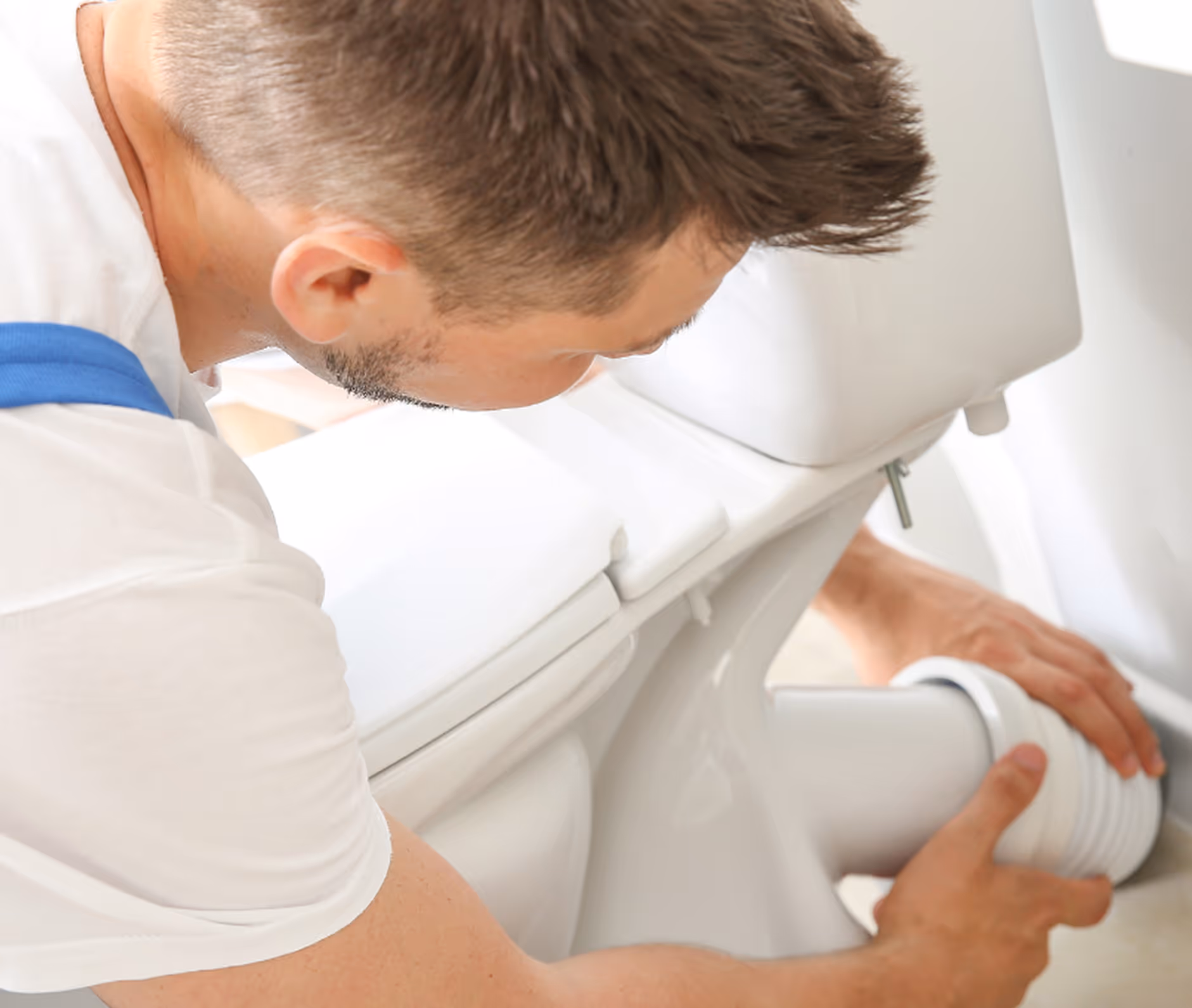 Mann installiert oder repariert einen Toilettenabfluss in einem Badezimmer.