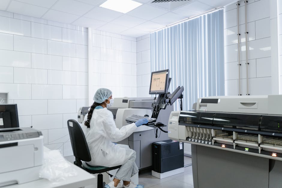 A laboratory technician wearing protective gear operates medical equipment in a sterile lab environment.