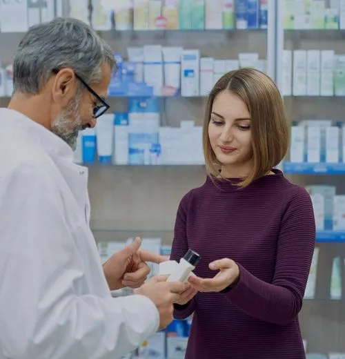 Pharmacist explaining medication to a female customer in a pharmacy.