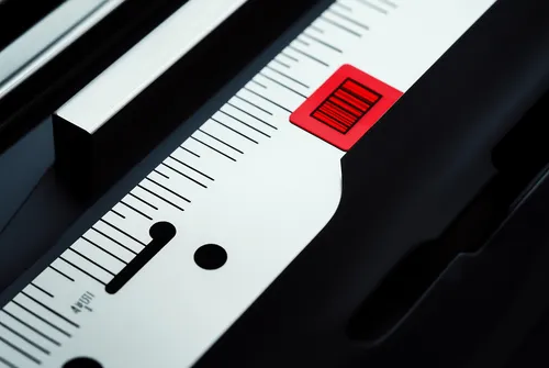 Close-up of a white ruler with black markings and a red sliding marker.