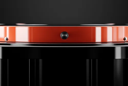 Close-up of a black and orange metallic cylindrical object with a small black square button or sensor in the center.