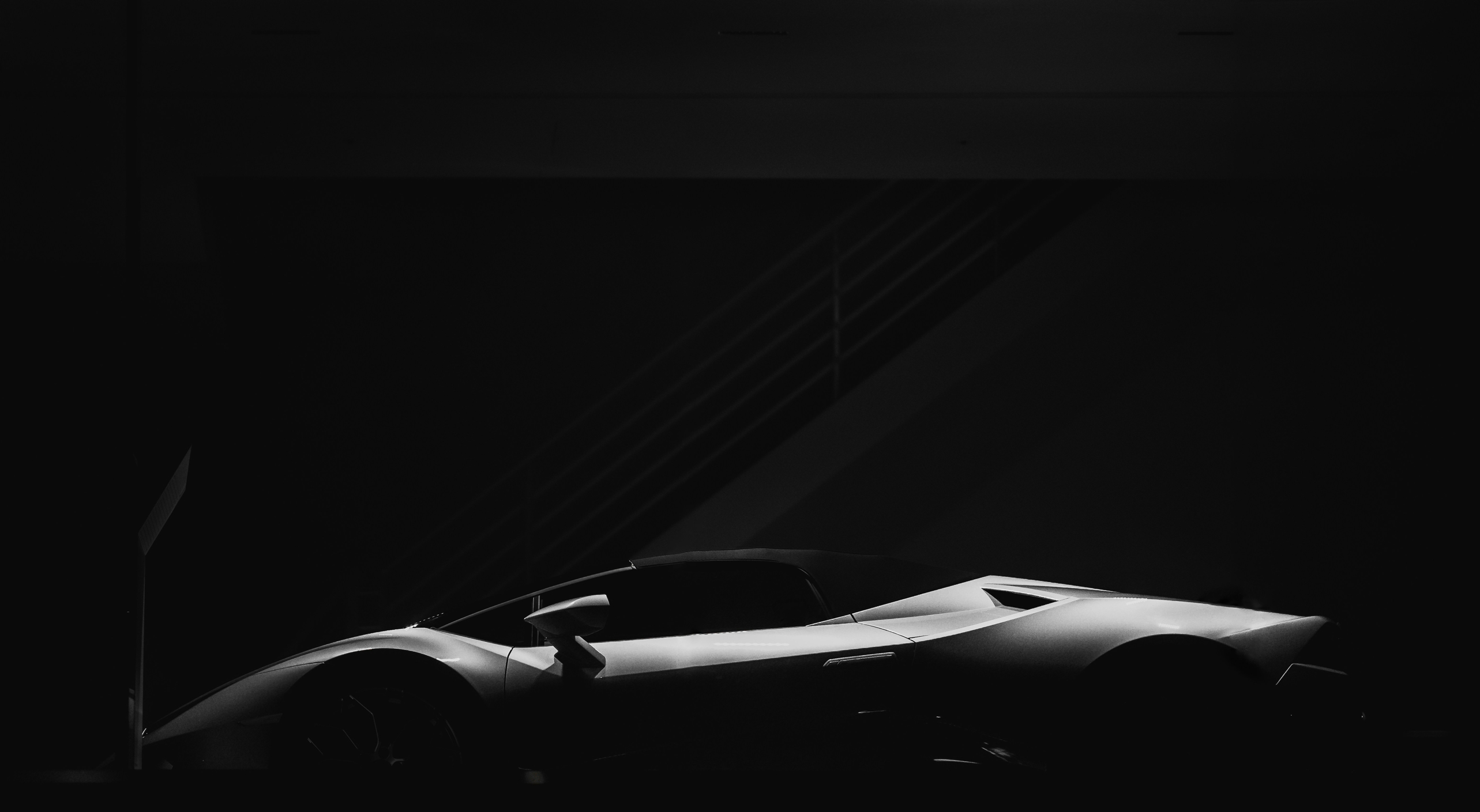 Side view of a sleek sports car in low light showing smooth curves and sharp design details.