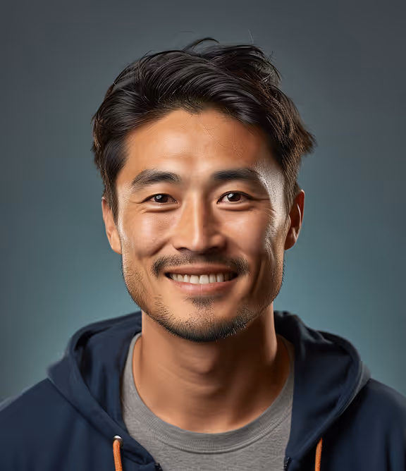 Portrait of a smiling young Asian man with short dark hair wearing a dark hoodie and gray shirt against a muted blue background.