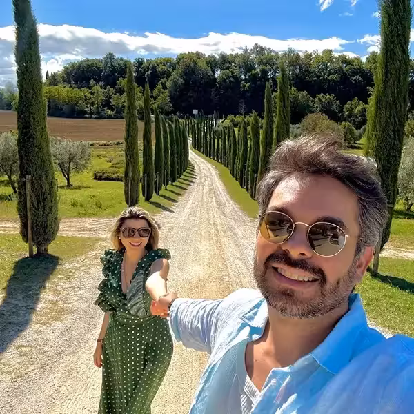 Milena y Carlos tomados de la mano en un camino de cipreses en la Toscana