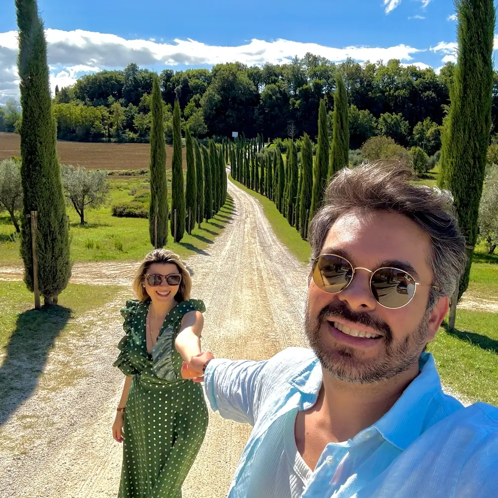 Milena y Carlos tomados de la mano en un camino de cipreses en la Toscana