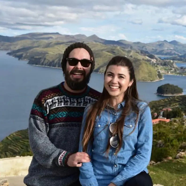 Milena y Carlos sonriendo con vista panorámica del lago Titicaca y las montañas