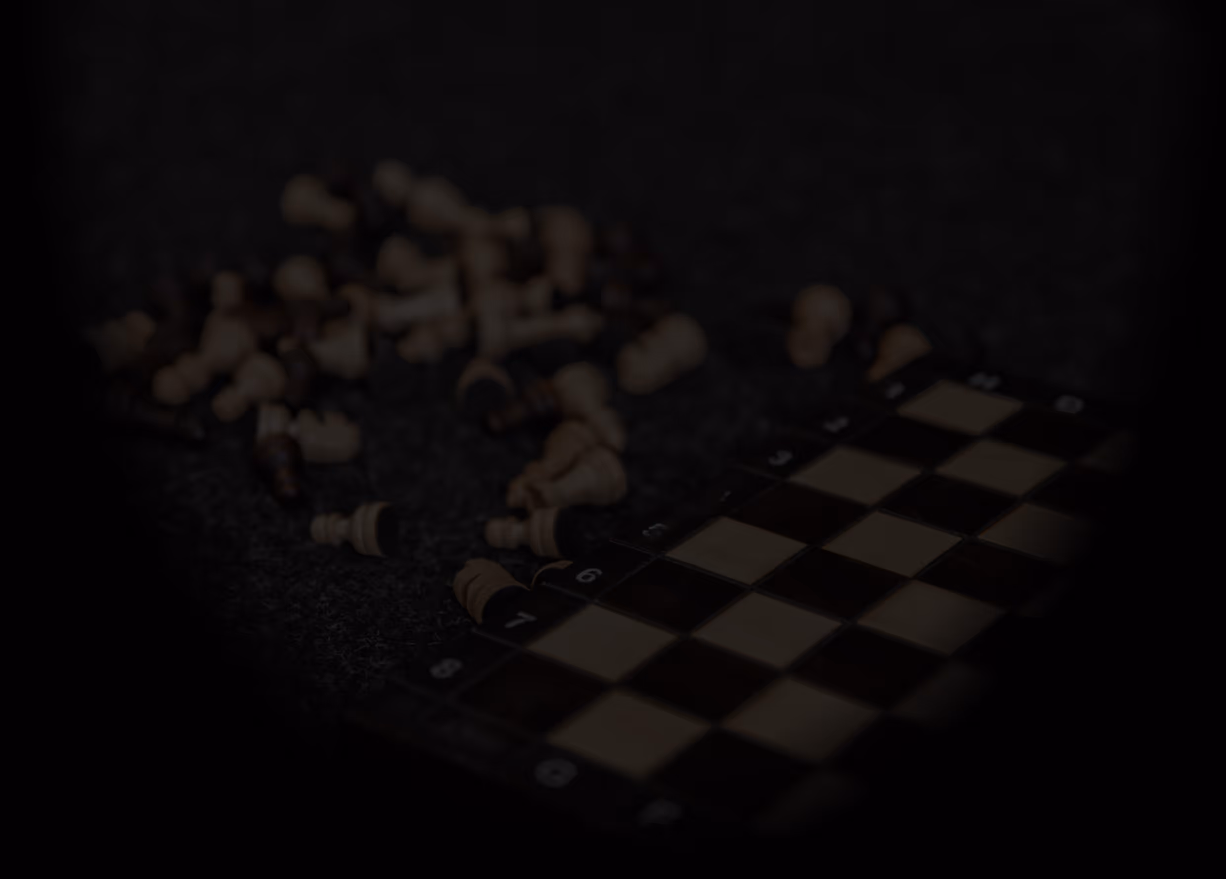 Ein zerlegtes Schachbrett mit verstreuten Schachfiguren auf einer dunklen Fläche.