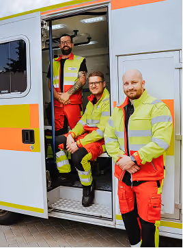 Mitarbeiter eines Rettungsdienstes vor einem Einsatzfahrzeug
