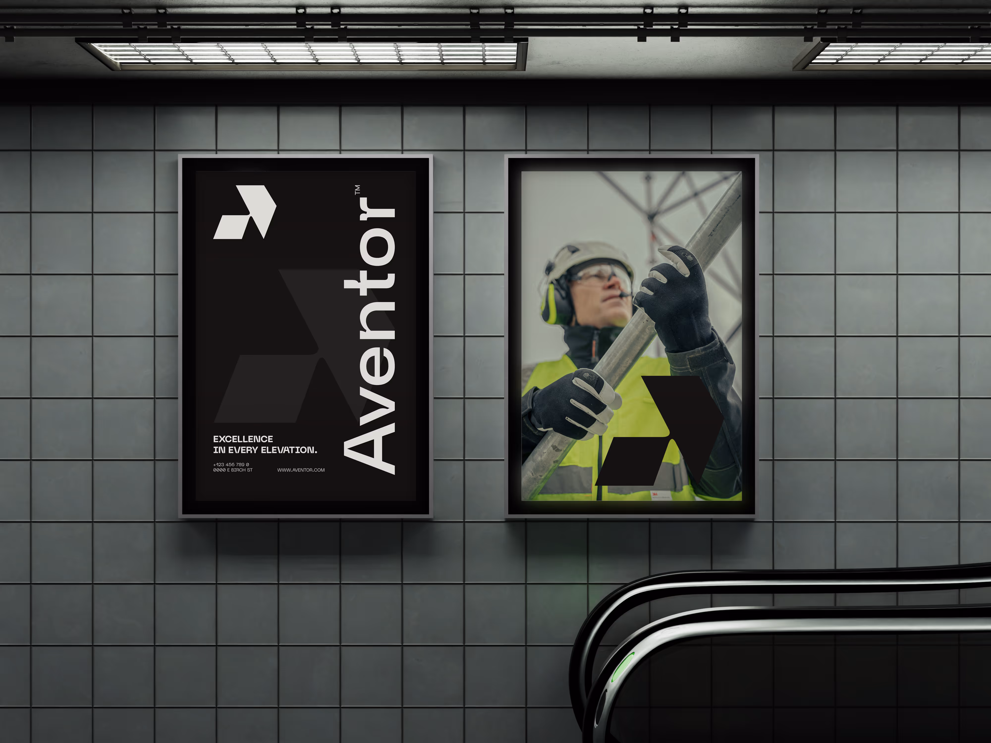 Two framed posters on tiled wall above escalator, one shows 'Aventor' text, the other a worker in safety gear.