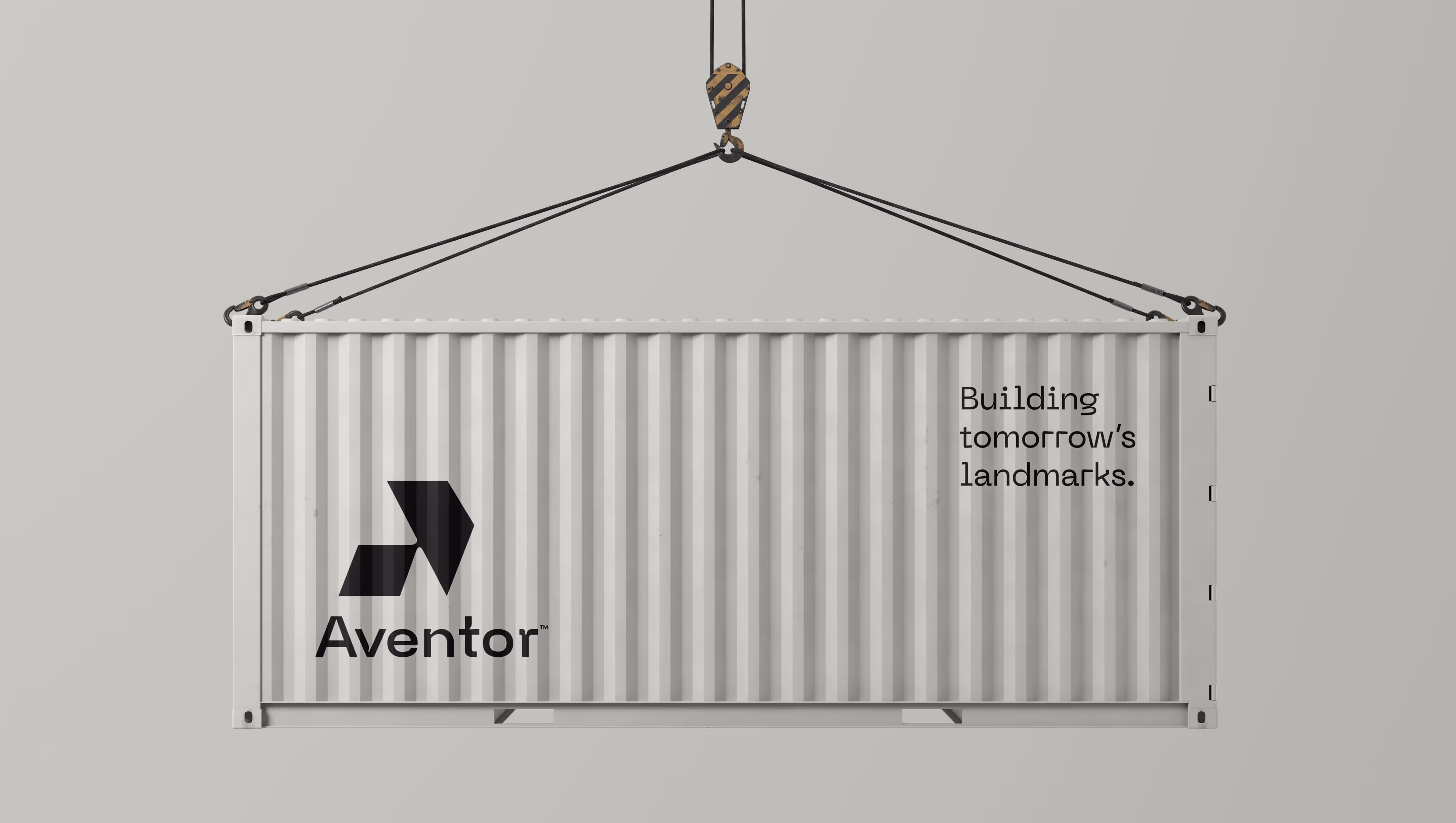 Gray shipping container suspended by cables with Aventor logo and text 'Building tomorrow's landmarks'.