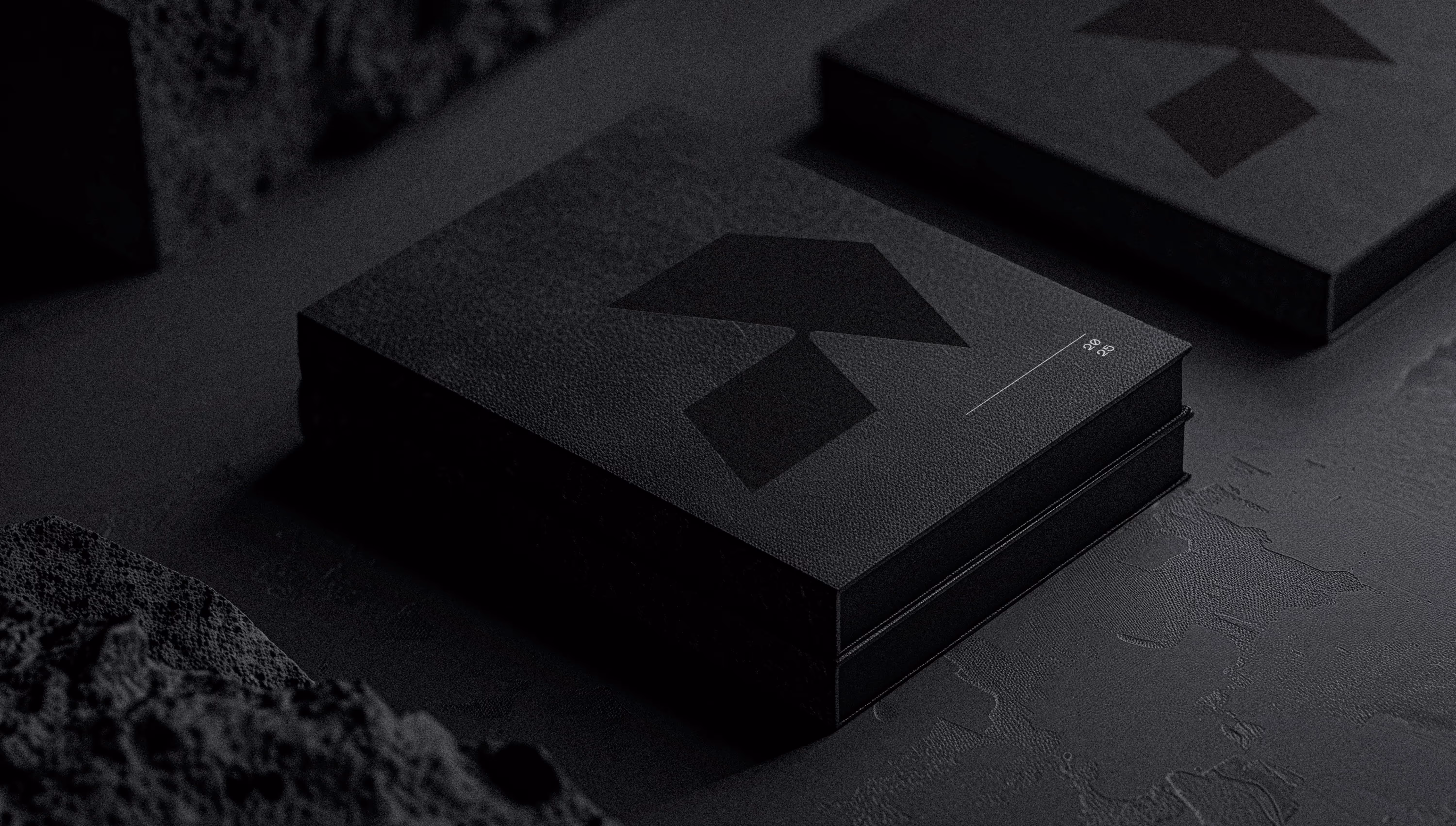 Black textured box with abstract shapes and '2025' text next to a similar box on a dark surface.