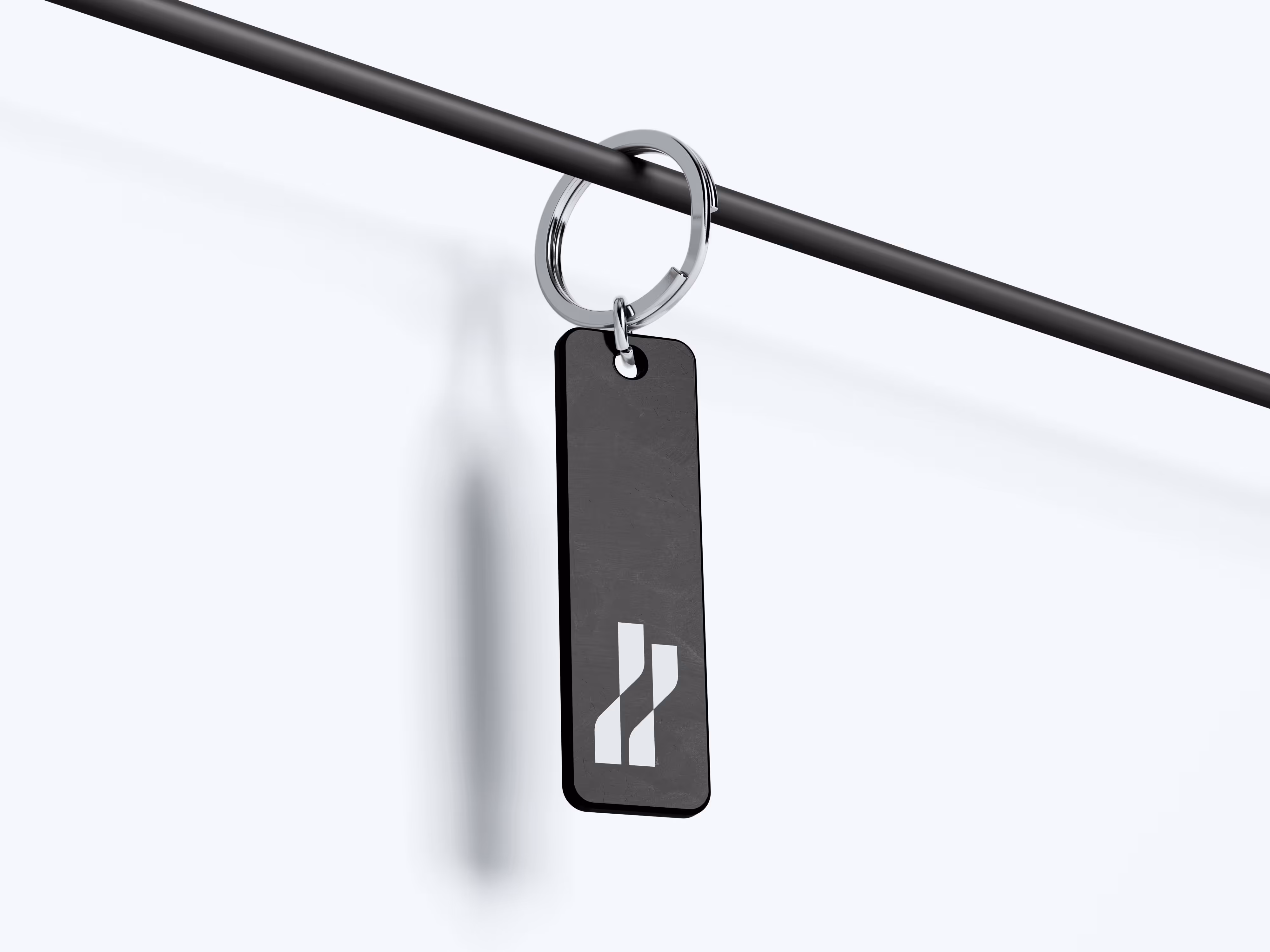 Black rectangular keychain with white abstract logo hanging on black rod.