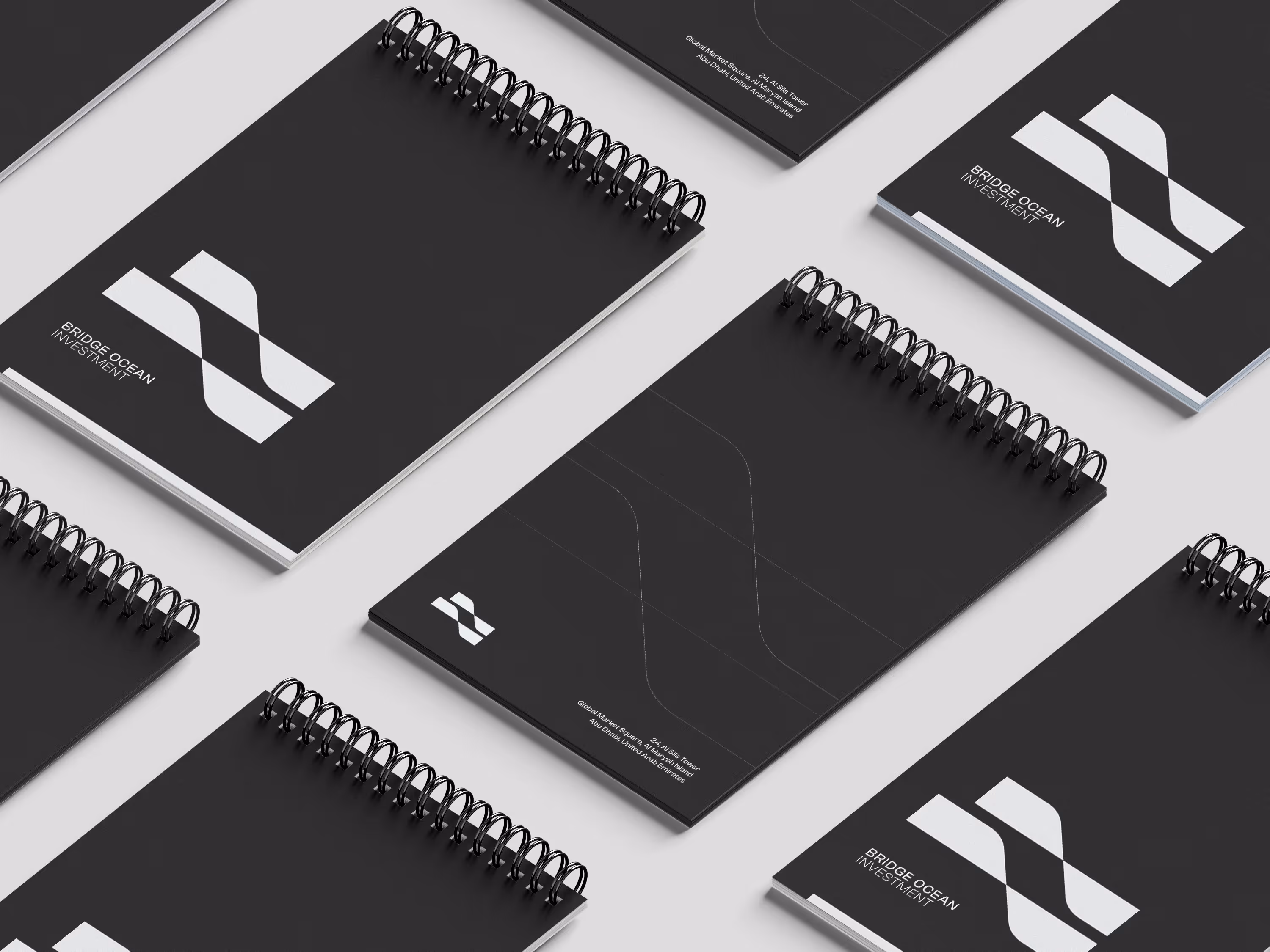 Multiple black spiral notepads with white Bridge Ocean Investment logo and text on a light background.
