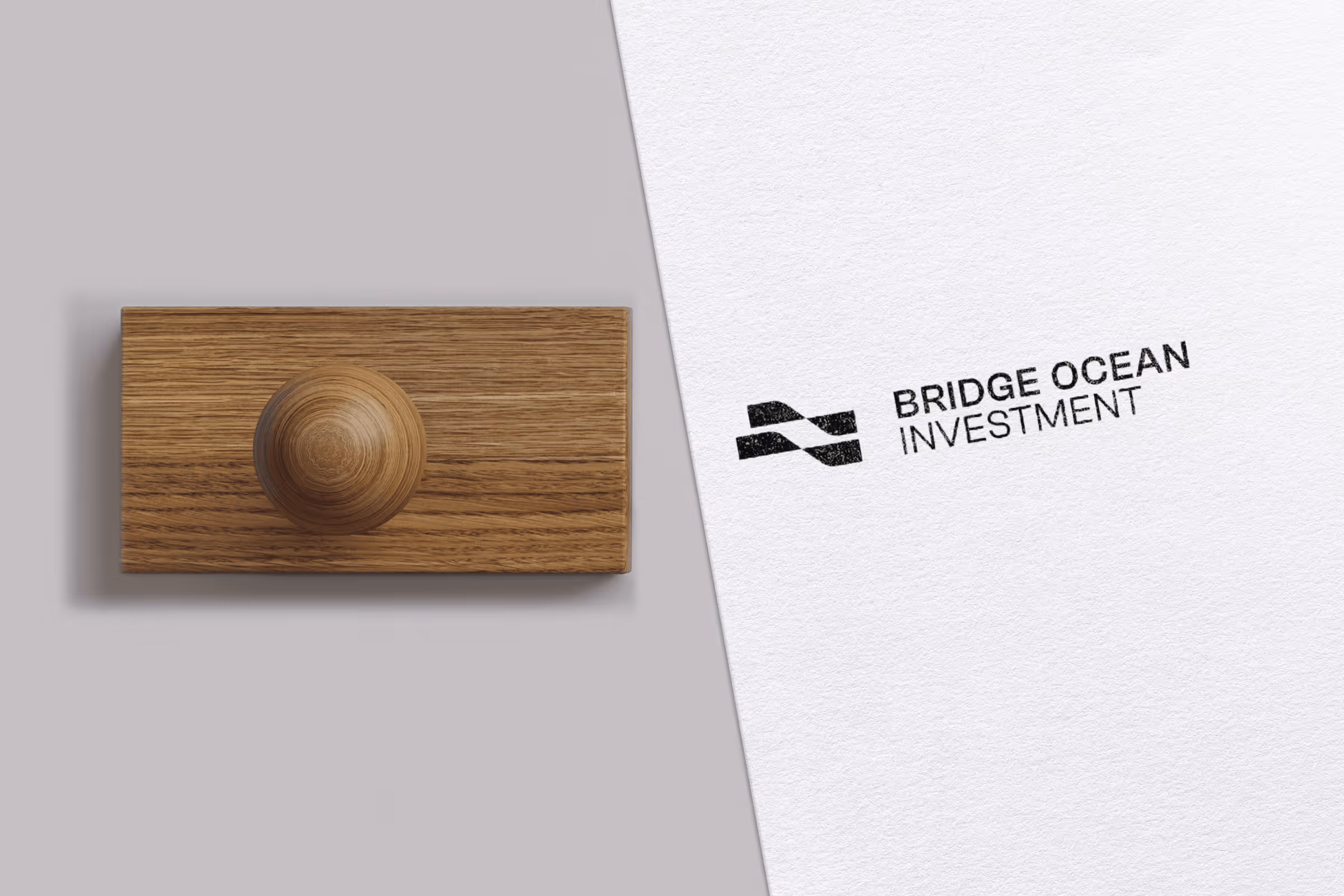 Wooden rubber stamp beside a stamped logo reading 'BRIDGE OCEAN INVESTMENT' on white paper.