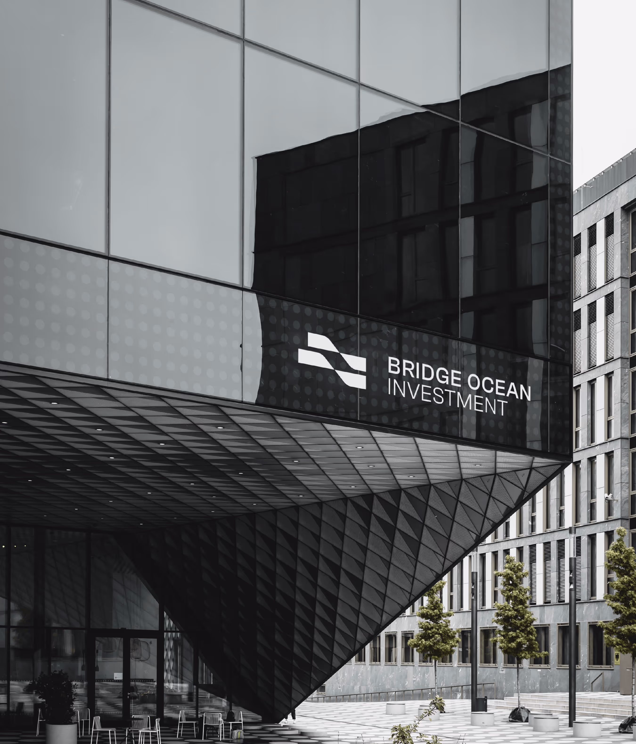 Modern building facade with Bridge Ocean Investment logo on reflective glass exterior.
