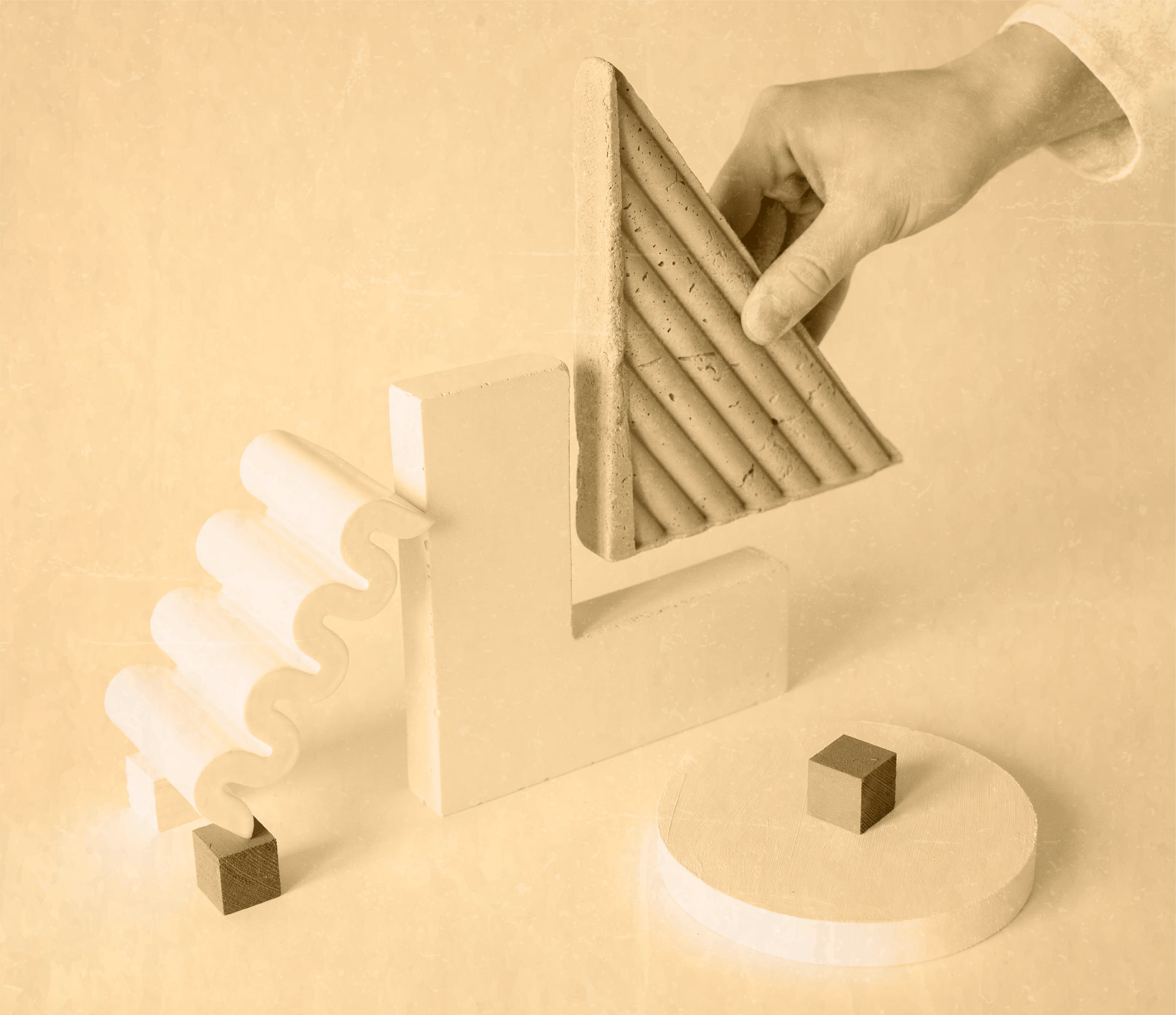 Hand placing a textured triangular block among various abstract geometric shapes on a beige surface.