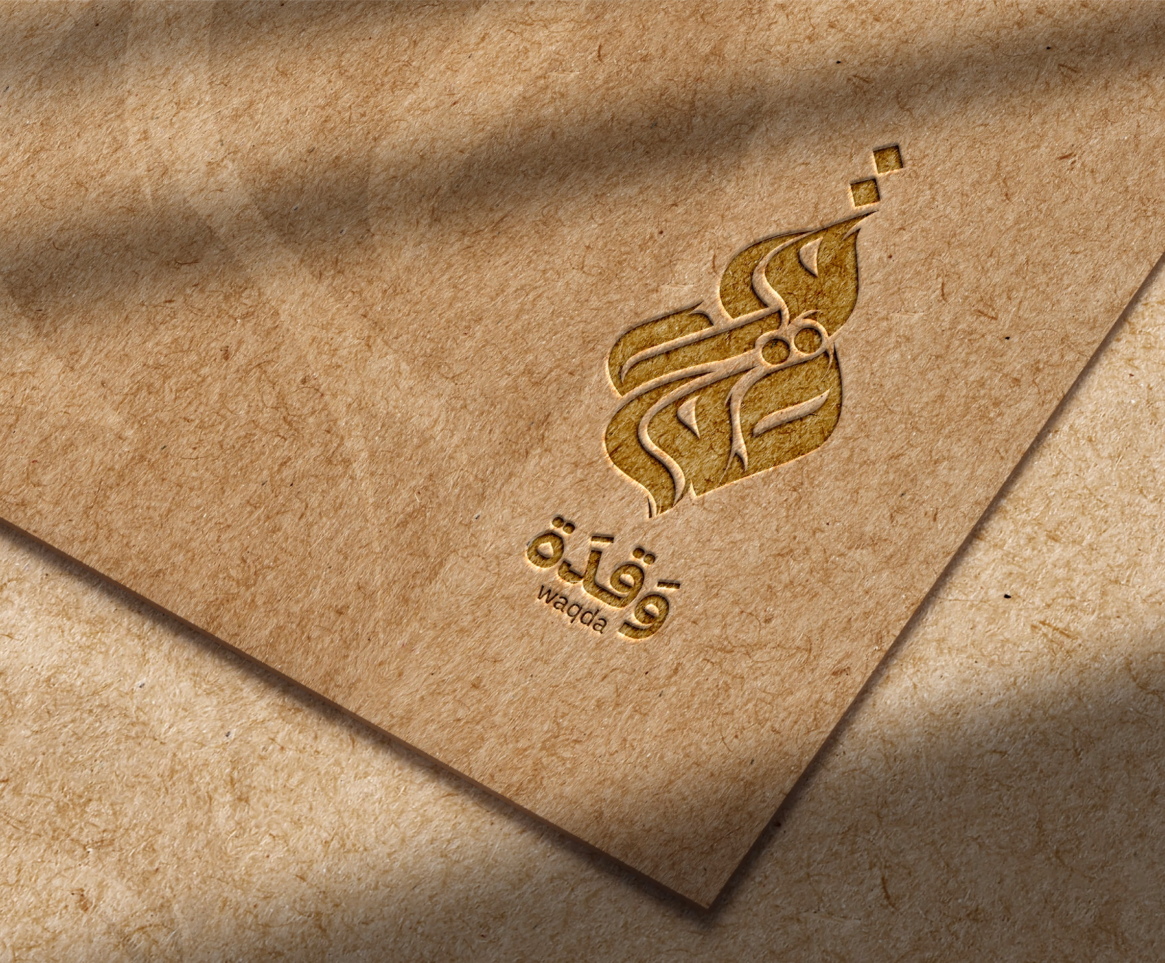 Embossed Arabic calligraphy logo with text ‘waqda’ on a brown textured paper surface.