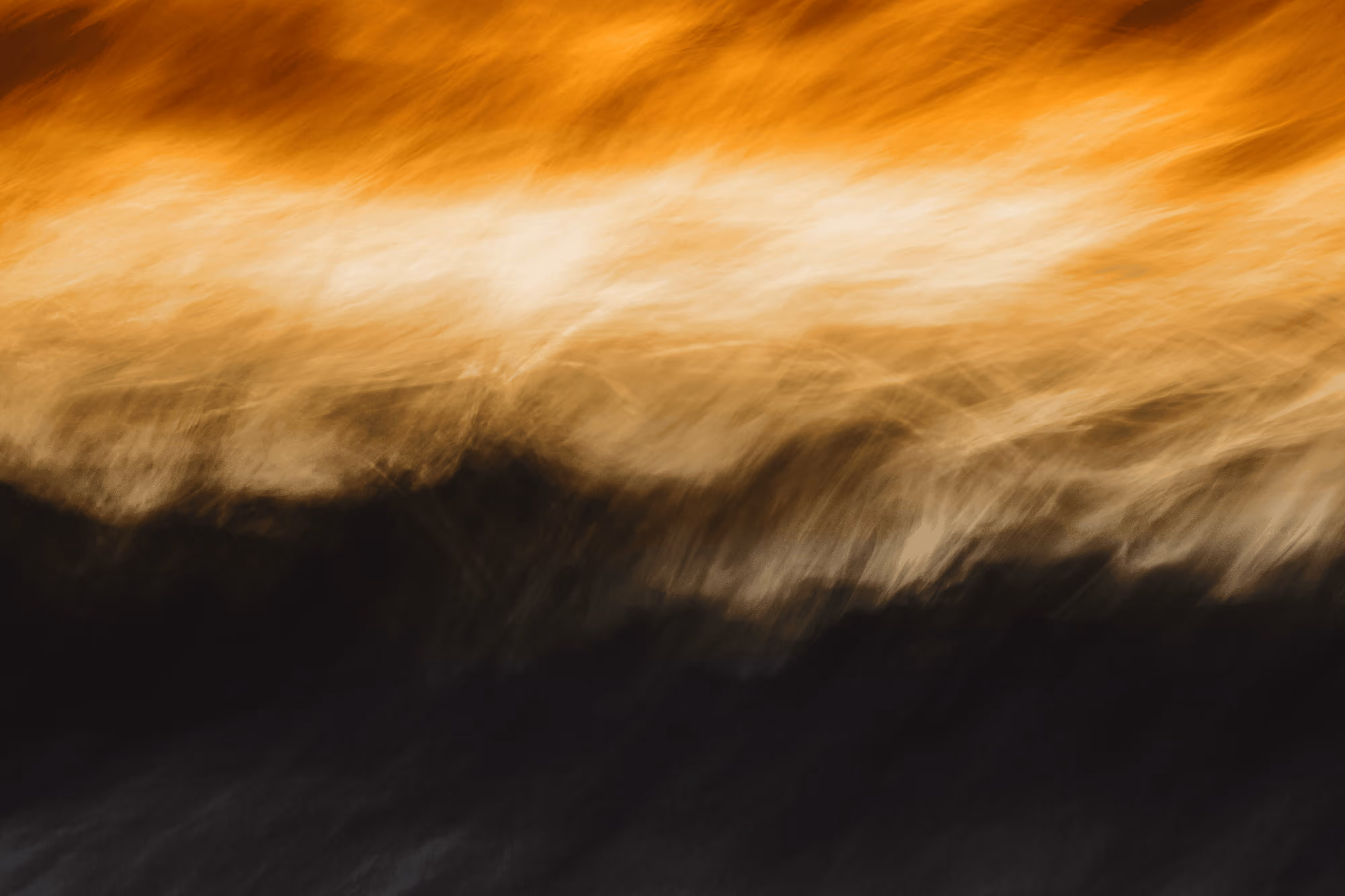 Abstract blurred image with streaks of orange, beige, and black colors blending horizontally.