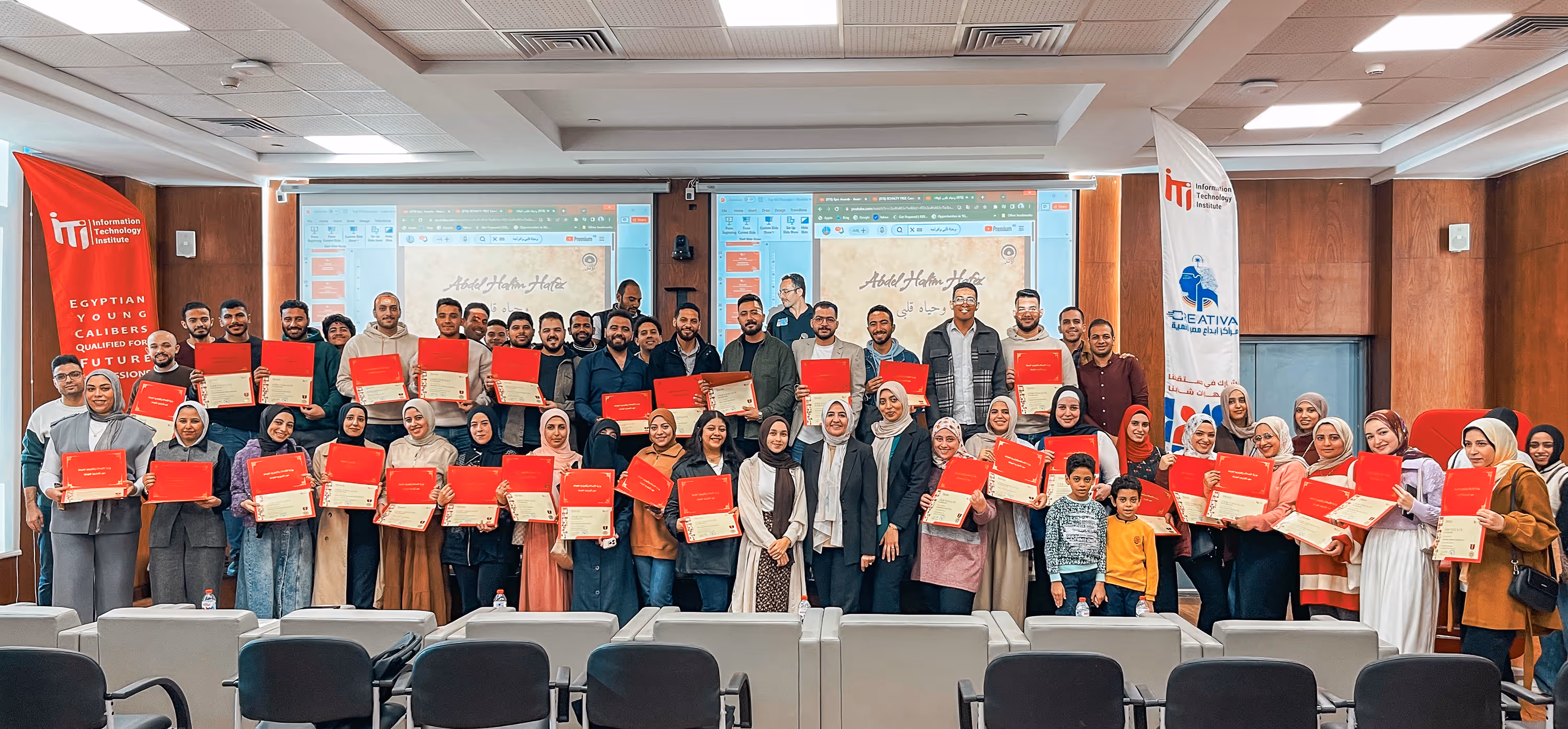 Group photo of diverse people holding red certificates in a conference room with ITI banners.