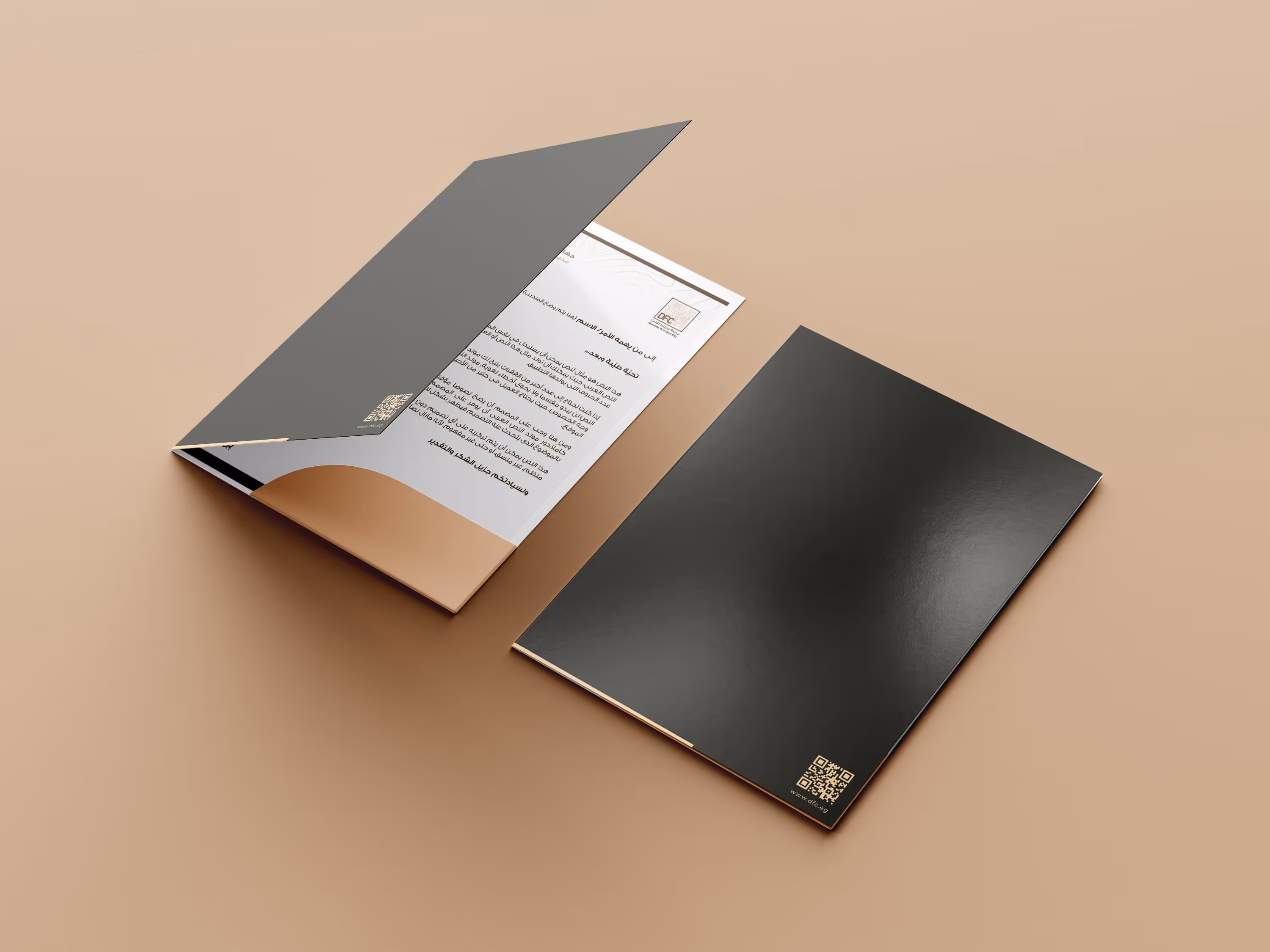 Two black folders on a beige surface, one open showing Arabic text and a QR code inside.