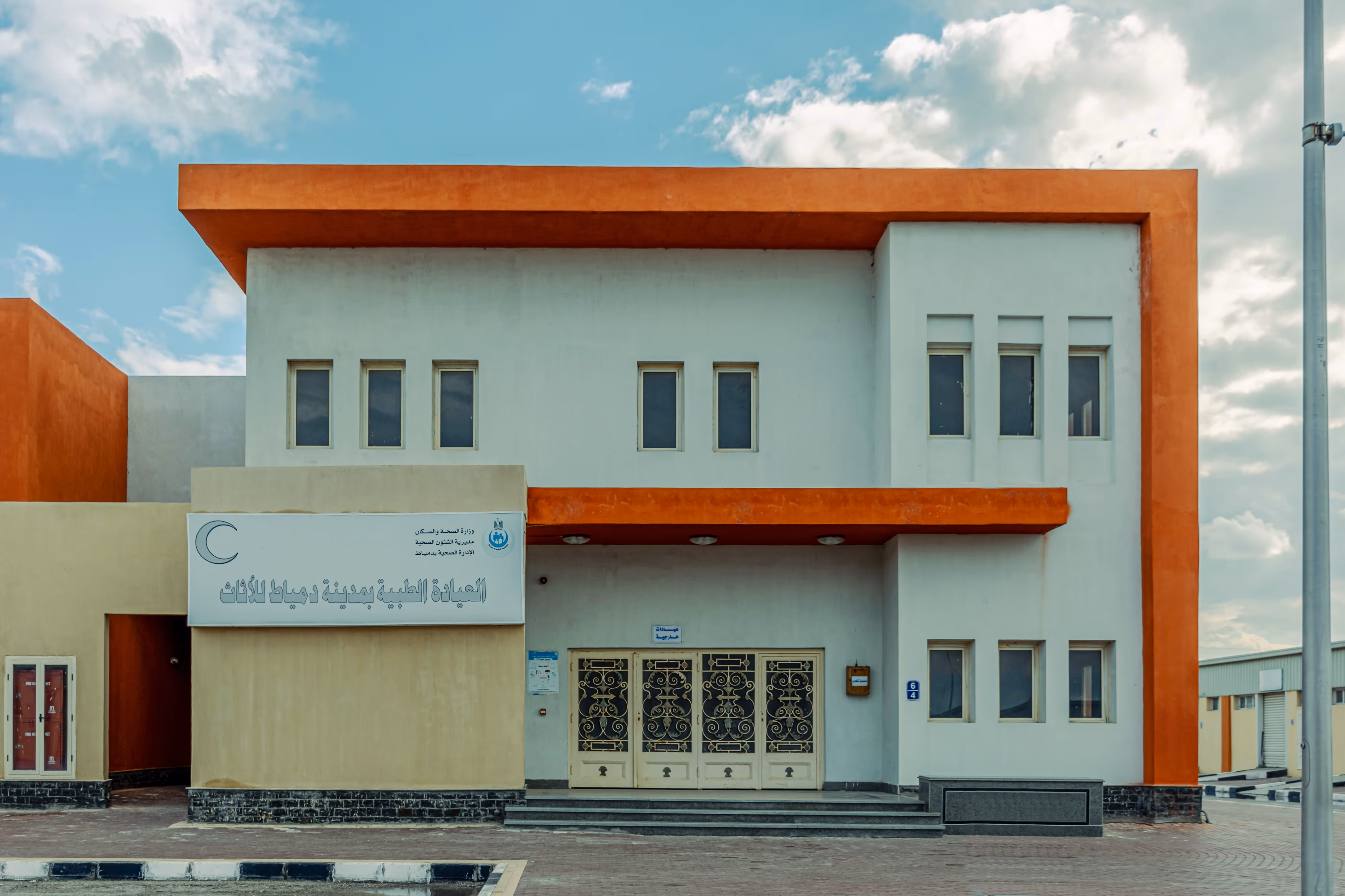 Modern two-story building with orange accents, multiple windows, and decorative front doors.