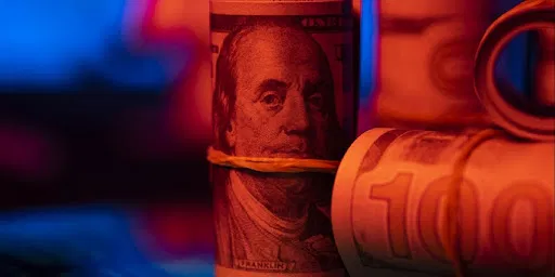 close-up-rolled-100-dollar-bills-blue-red-lighting.webp