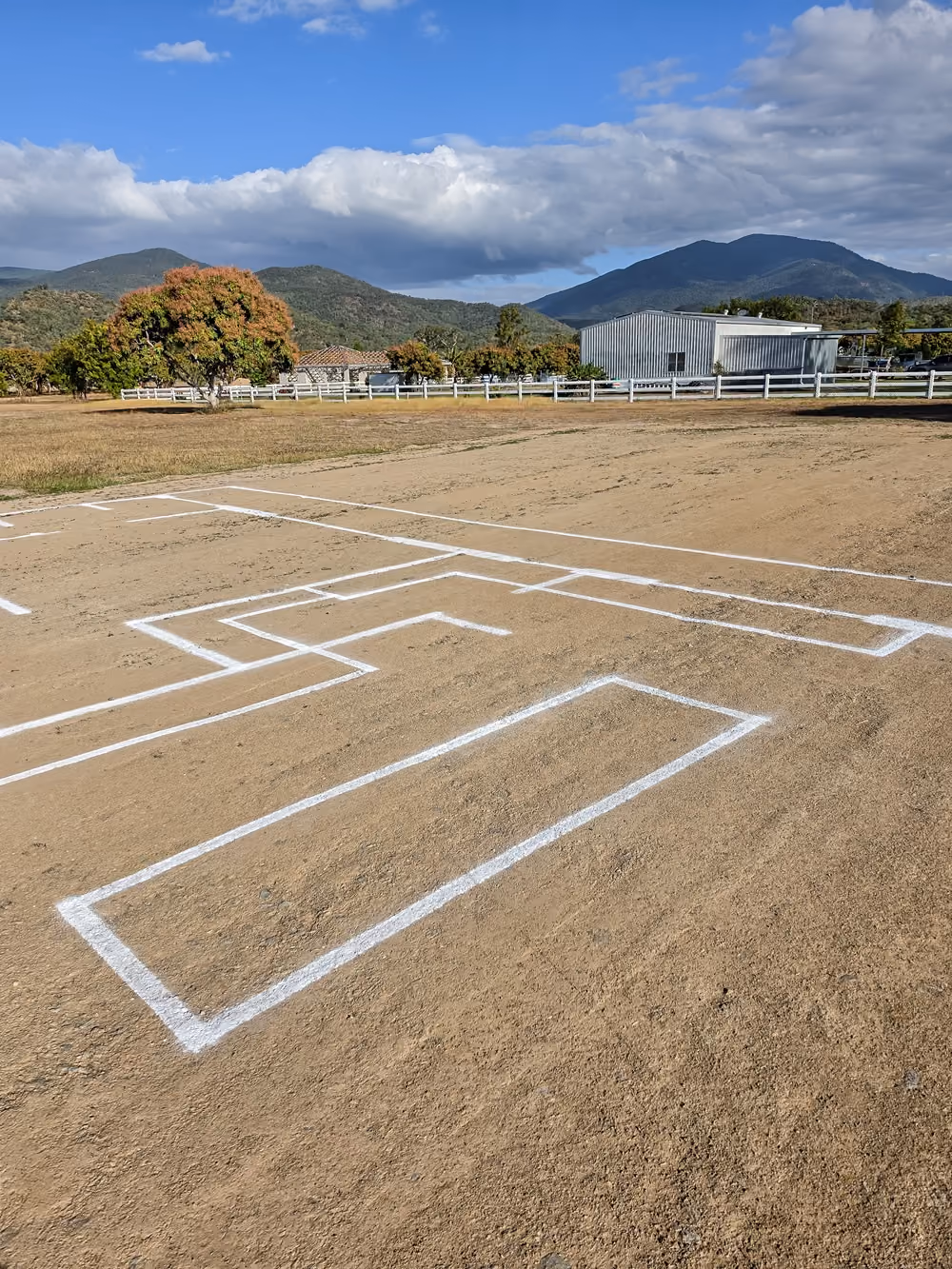 Full-scale house layout marked on a cleared block with mountains in the background.