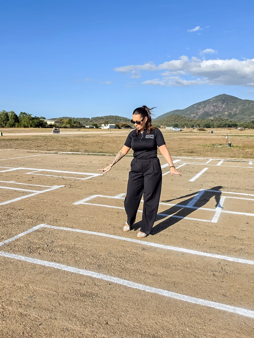 A person standing within a full-scale house layout marked on a rural block.