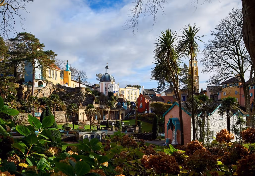 View of colorful buildings and lush greenery in a picturesque village under a cloudy sky.