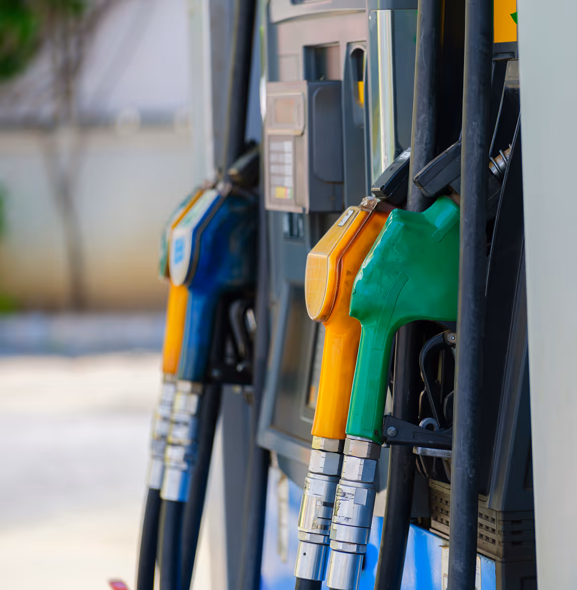 Close-up of green, orange, and blue fuel nozzles at a gas station pump.