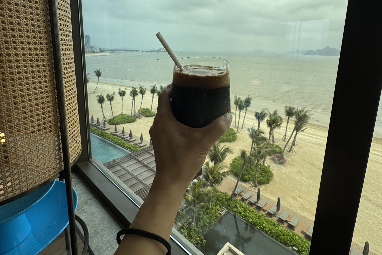 Woman holding Vietnamese coffee with Halong Bay view from club lounge