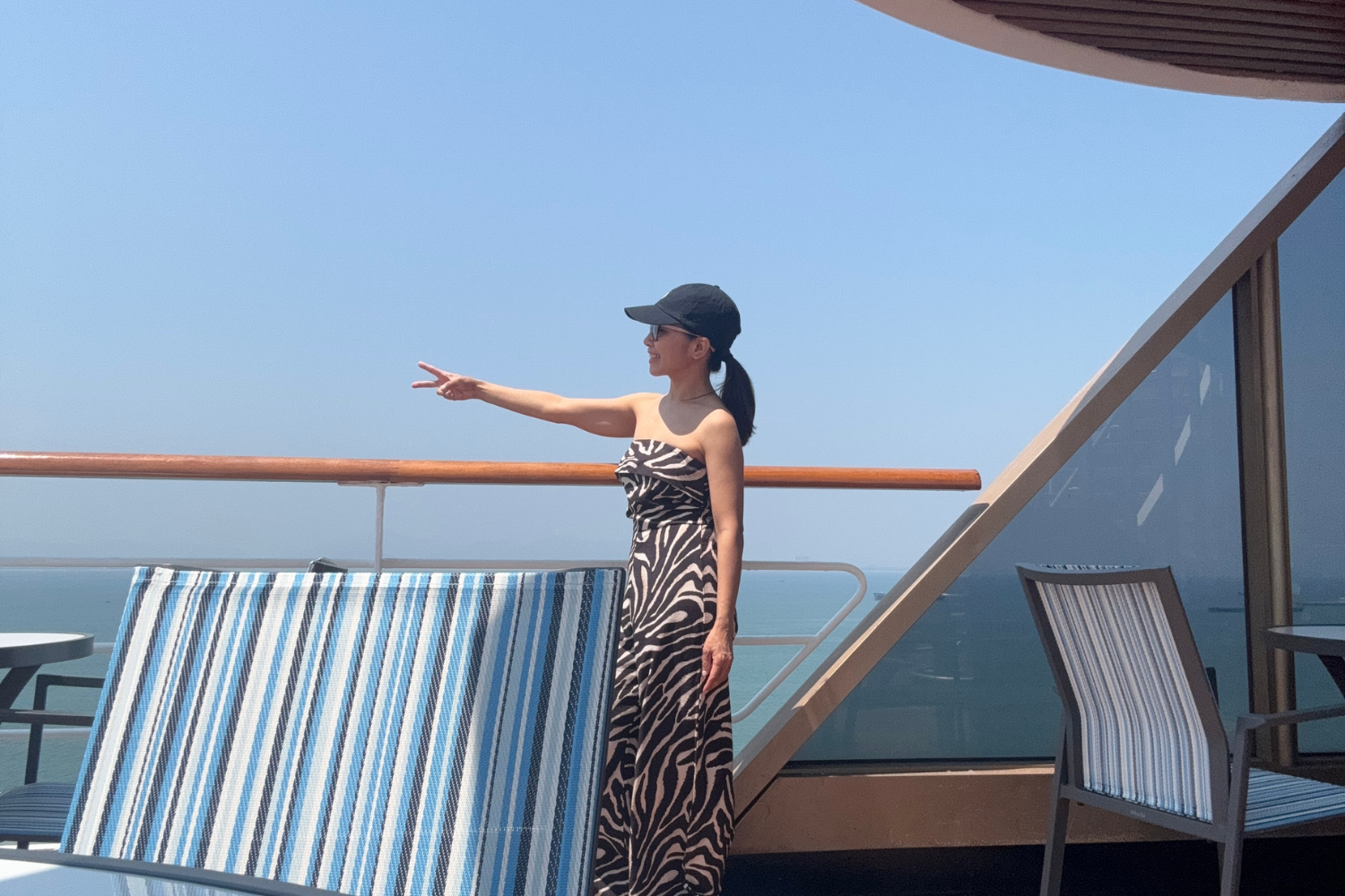 Woman on Deck 8 of cruise ship making peace sign while looking toward ocean