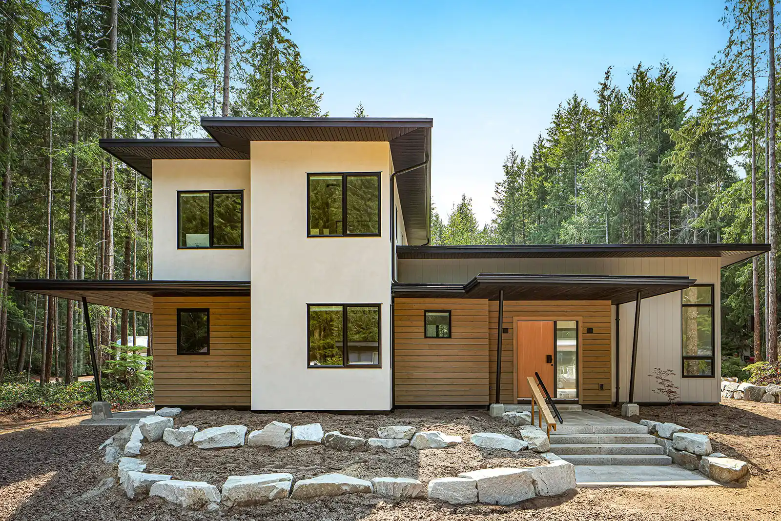 Pine Forest custom home exterior with natural wood and light siding blending into northeast Vancouver Island forest setting