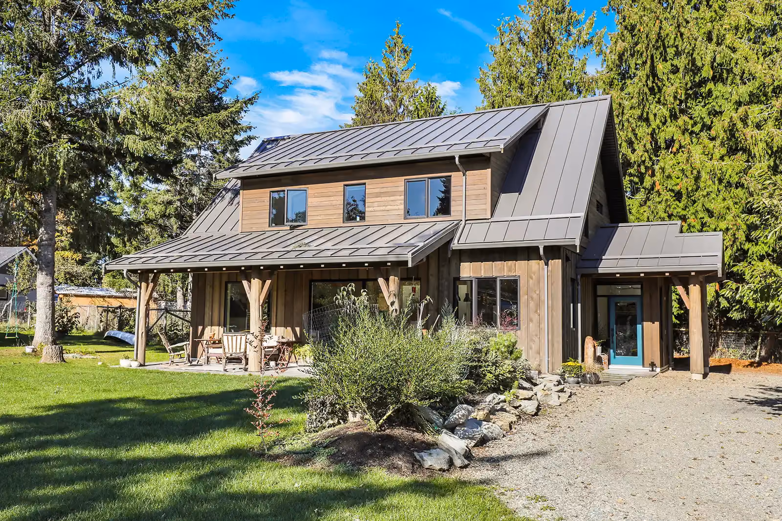 Rustic Retreat modern farmhouse exterior in Cumberland BC with cedar plank siding, metal roof, and covered patio
