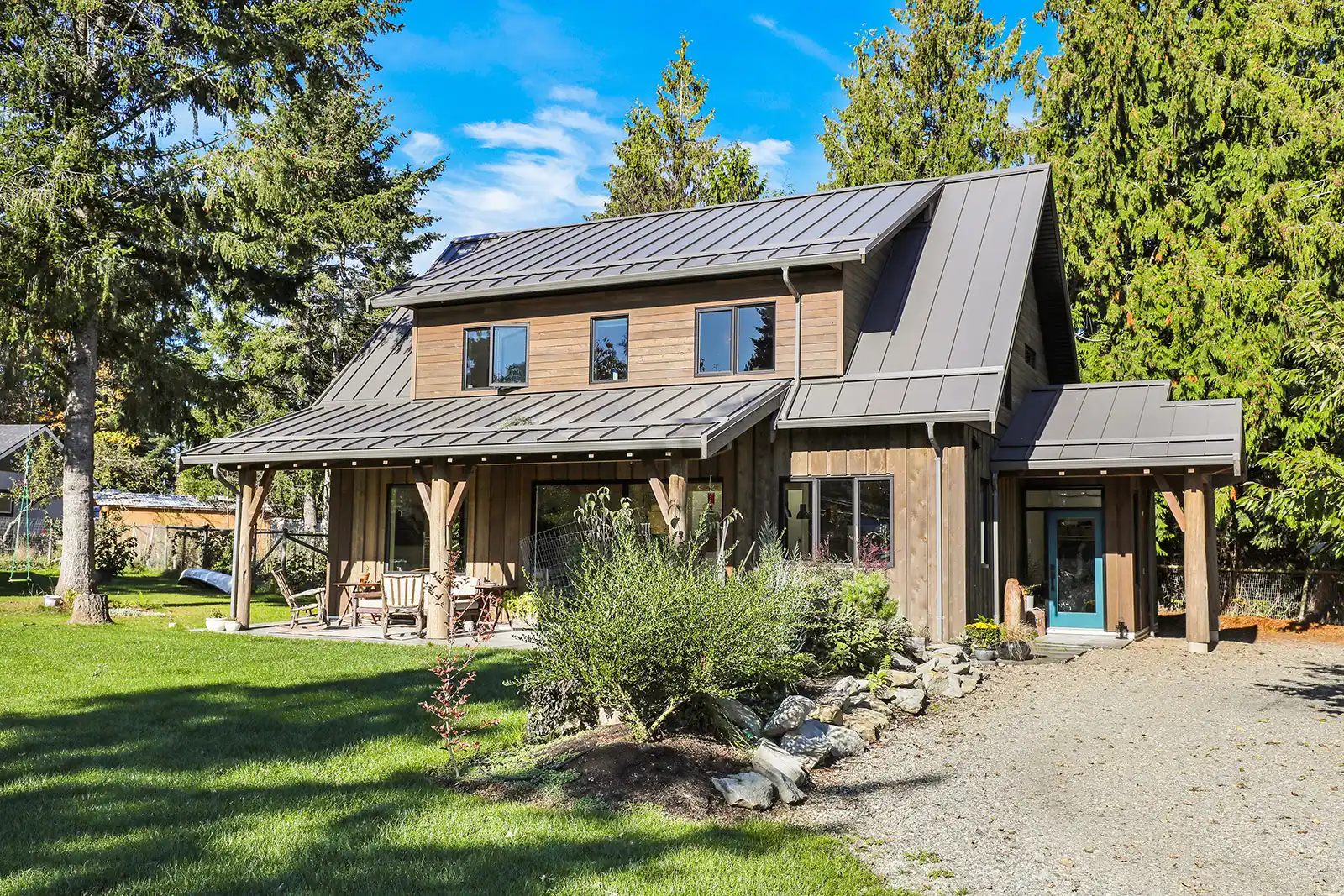 Rustic Retreat modern farmhouse exterior in Cumberland BC with cedar plank siding, metal roof, and covered patio