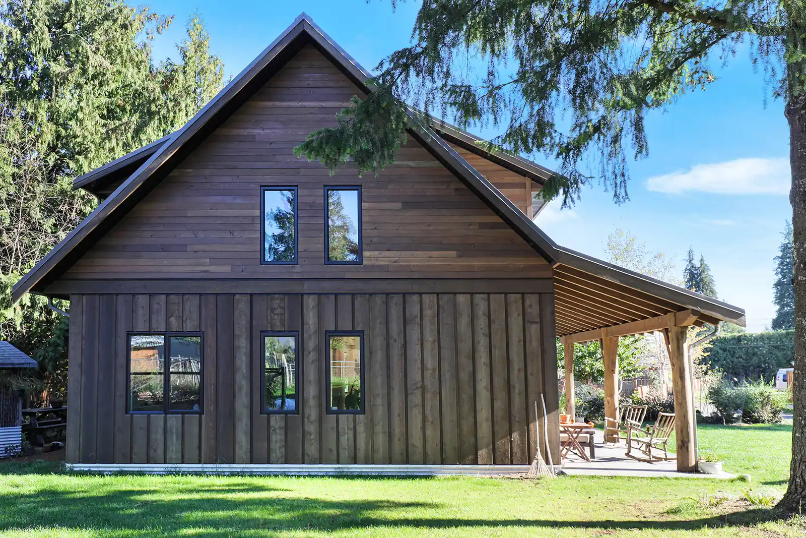 Exterior of Rustic Retreat showcasing cedar plank siding, muted farmhouse palette, and wrap-around covered deck