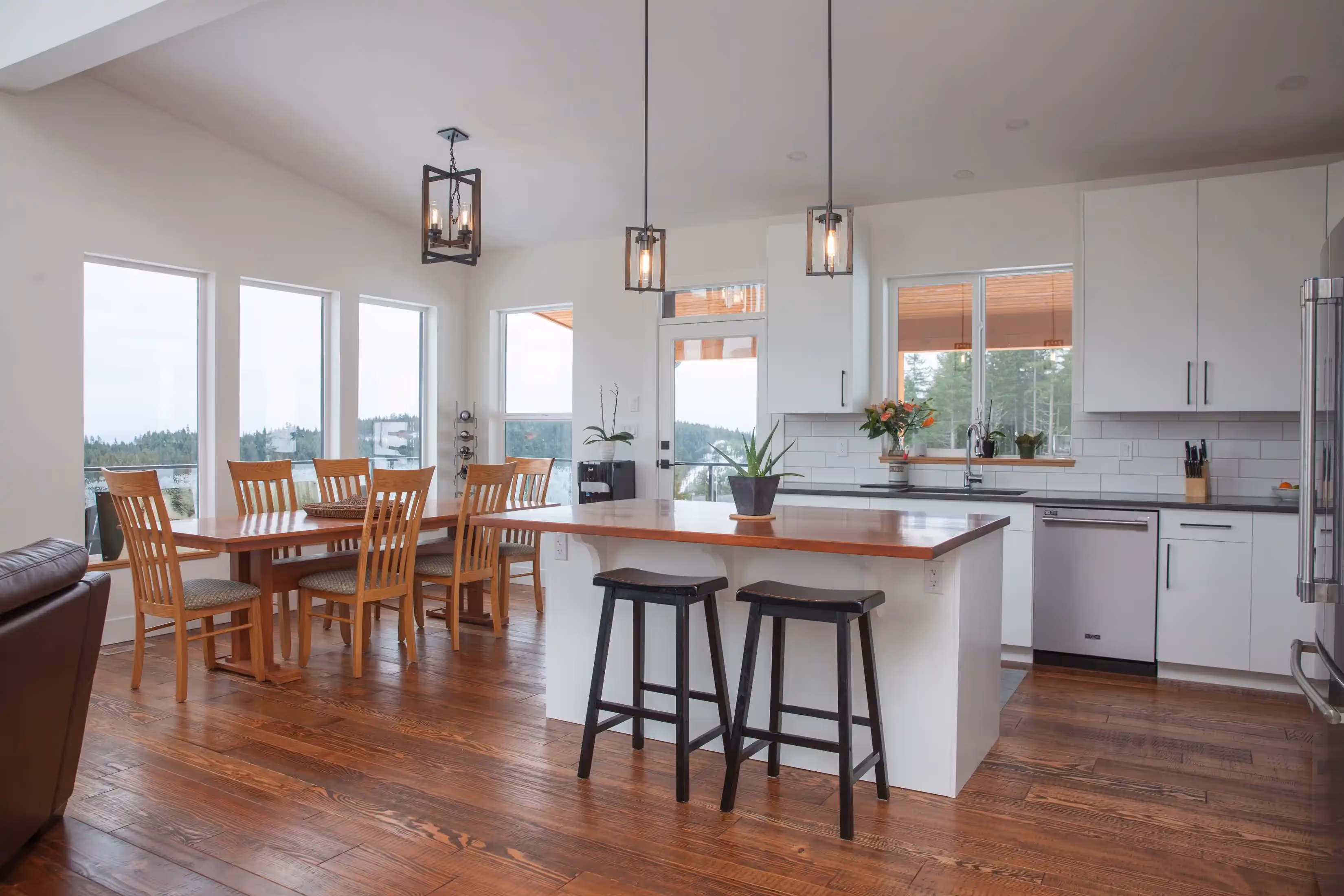 Spacious great room in The Edge with asymmetrical shed roof, cozy seating area, and expansive forest view deck