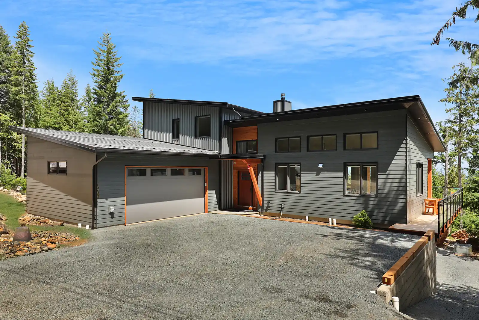 Exterior view of Mountain Mist luxury home at Forbidden Plateau with spacious deck and panoramic forest and mountain backdrop