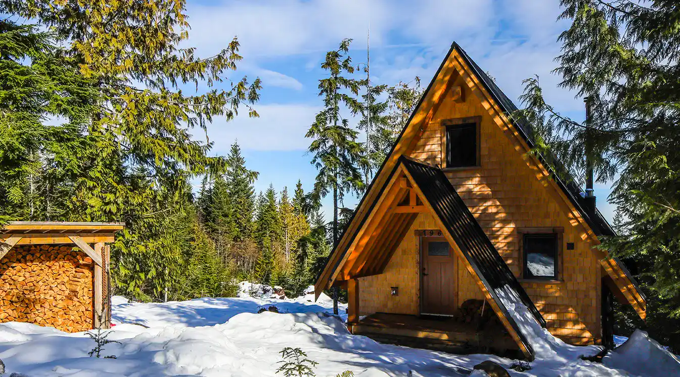 A Plus bespoke A-frame cabin exterior at Forbidden Plateau with timber framing, cedar shake, and black metal roofing