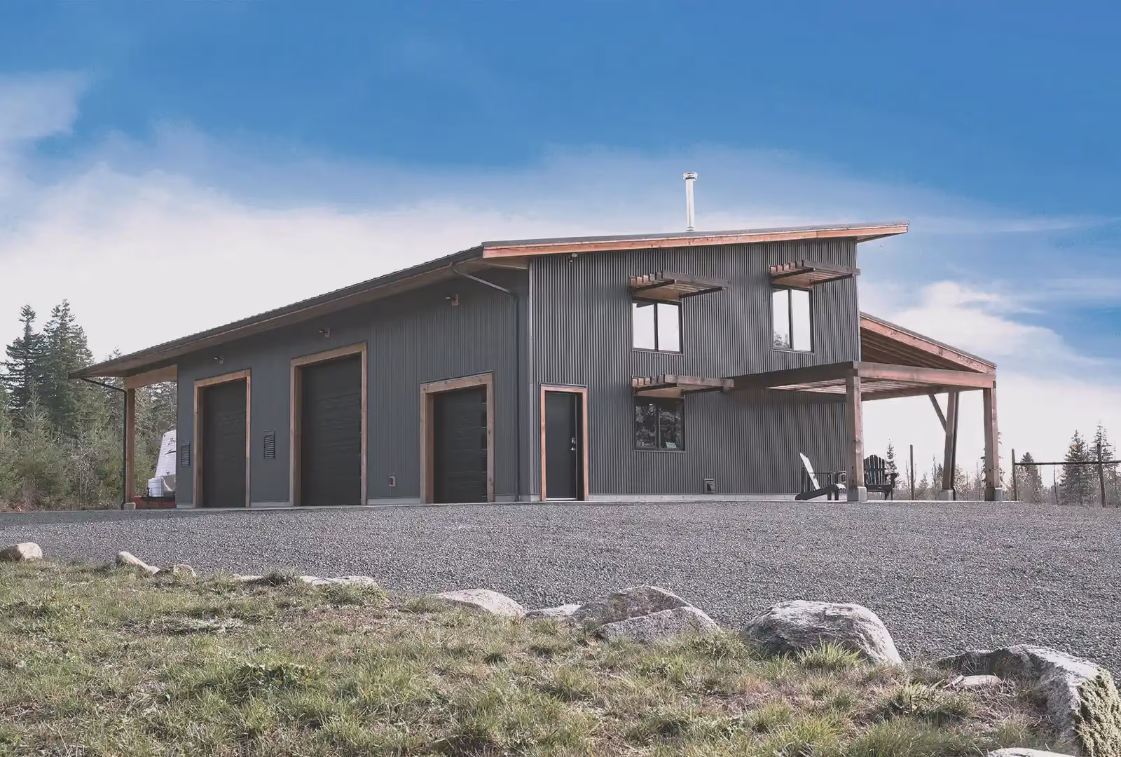 Asgard Farm three-bay workshop exterior with shade fins, curved green roof, and mountain orchard backdrop