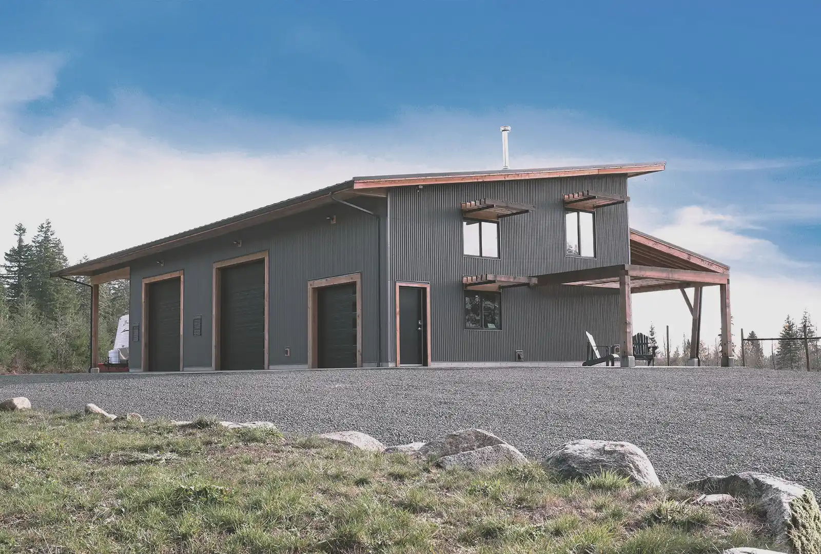 Asgard Farm three-bay workshop exterior with shade fins, curved green roof, and mountain orchard backdrop