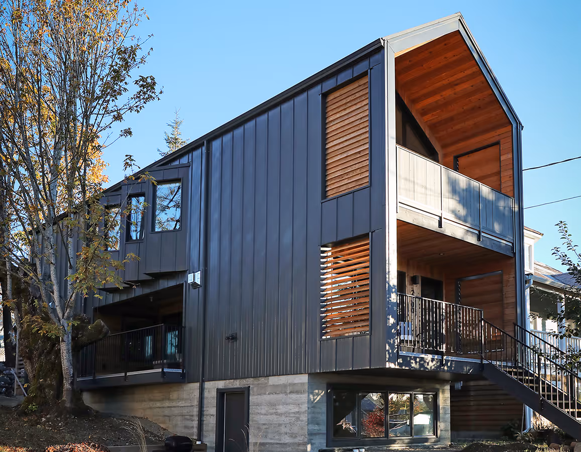Dark Side custom home exterior in Cumberland BC with striking metal cladding, sharp angles, and warm wood accents