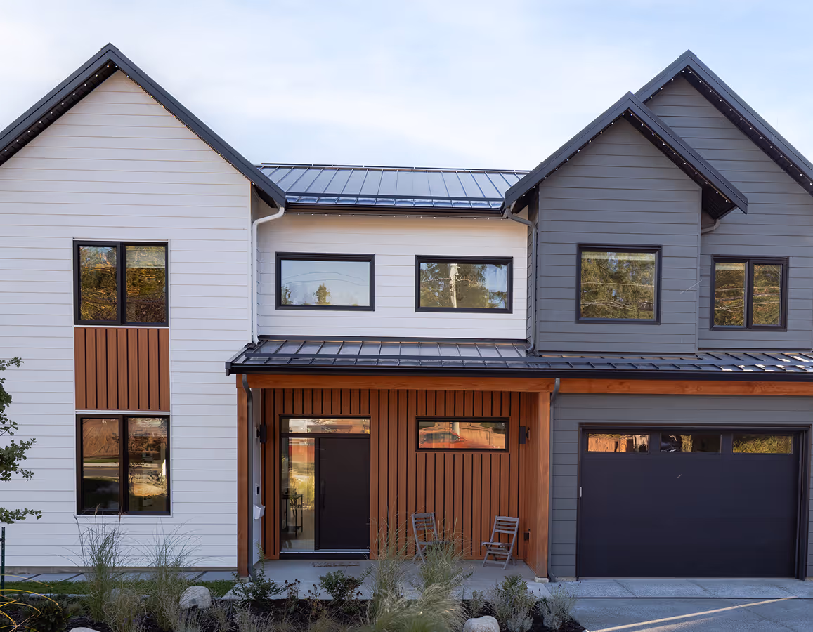 The Second Act modern farmhouse exterior in Comox with solar panels, post-wild landscaping, and bold clean lines