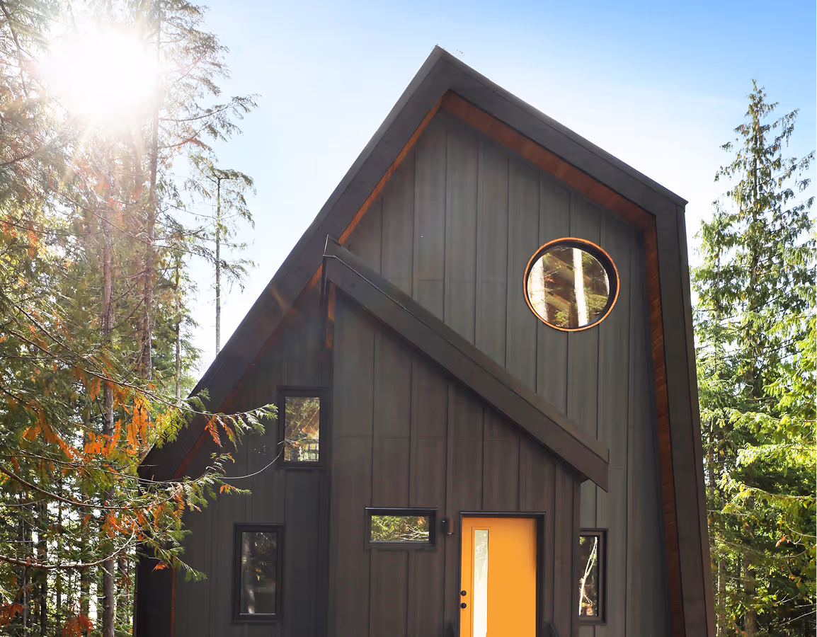 Forbidden Black A-frame exterior on Forbidden Plateau with all-black cladding, sharp angles, and vibrant orange front door