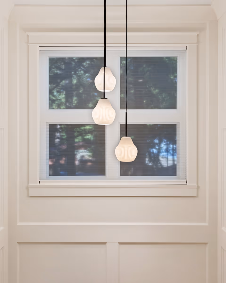 Modern pendant lights hanging in front of a large window in a Facet custom home interior