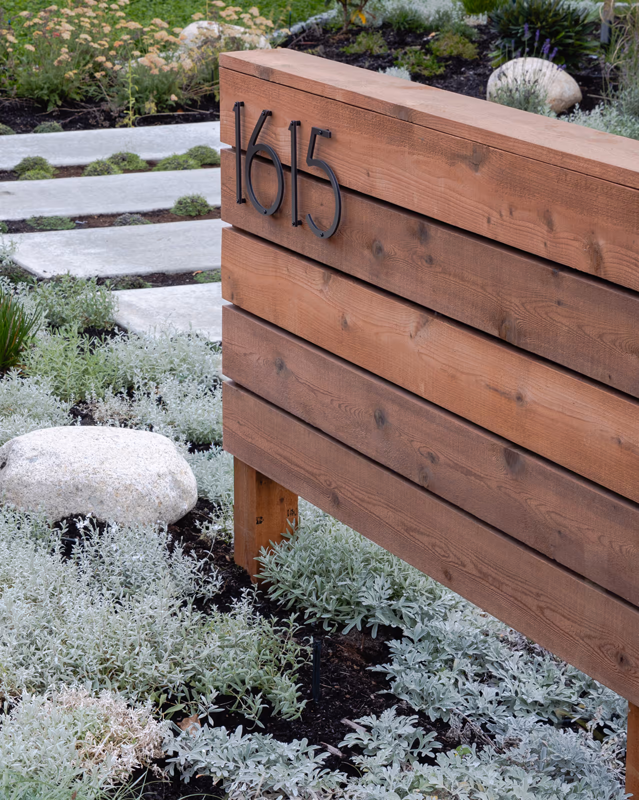 Wooden house number sign with metal address plate on exterior of Facet custom home