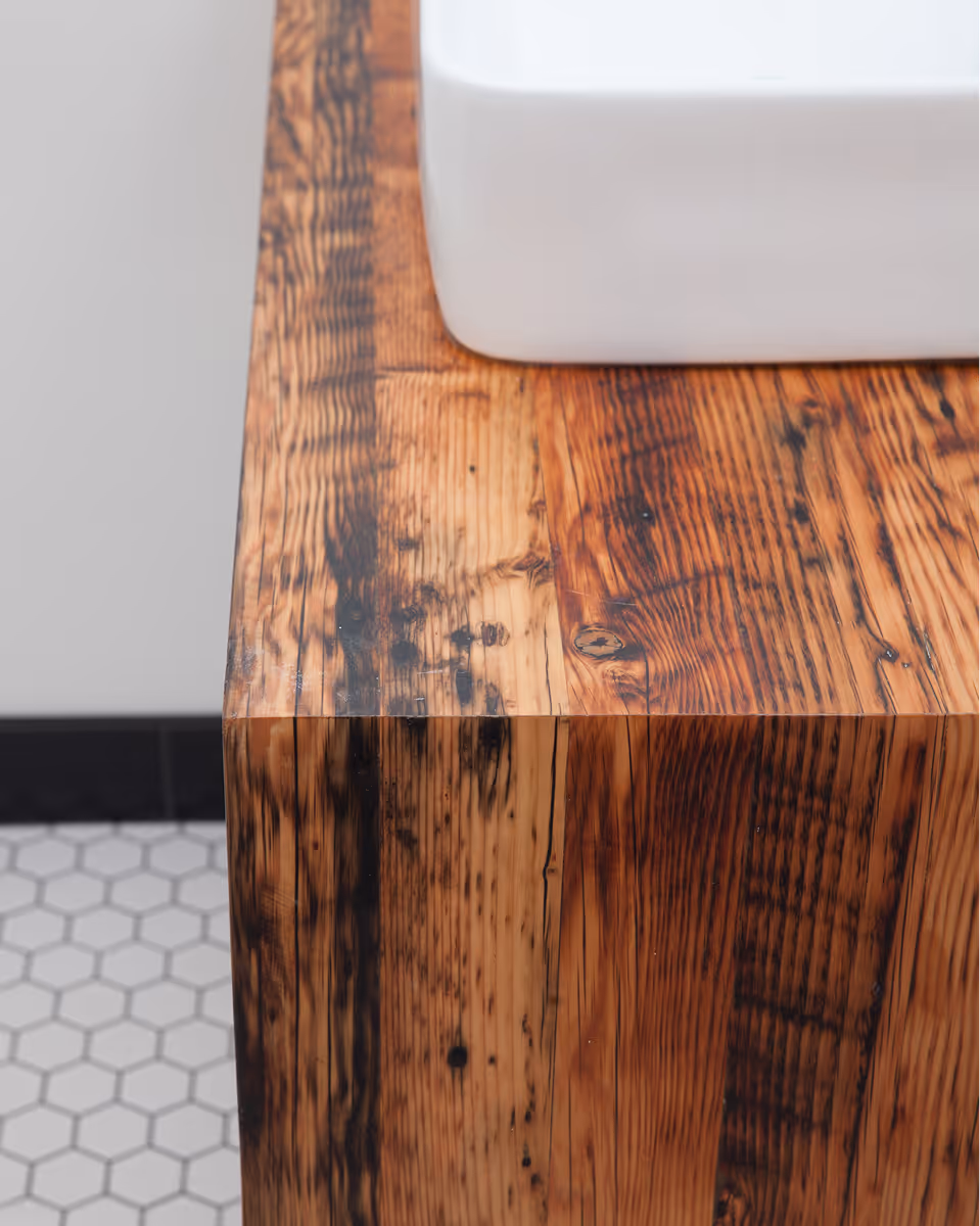 Custom wooden bathroom vanity with warm wood grain and nicely tiled floor in Facet home renovation