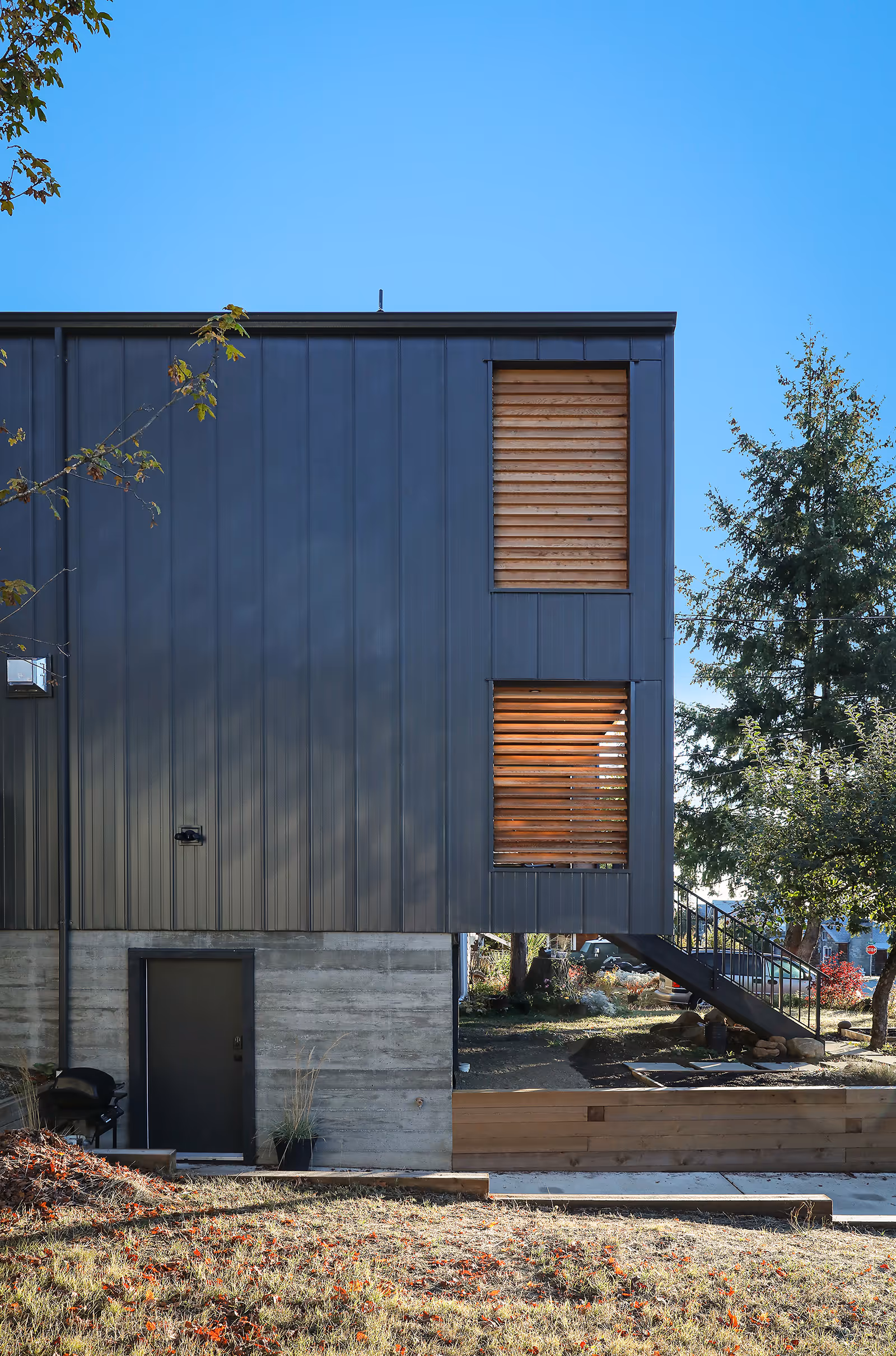 Street-facing view of Dark Side modern Scandinavian home in Cumberland with standing seam metal siding and privacy louvers