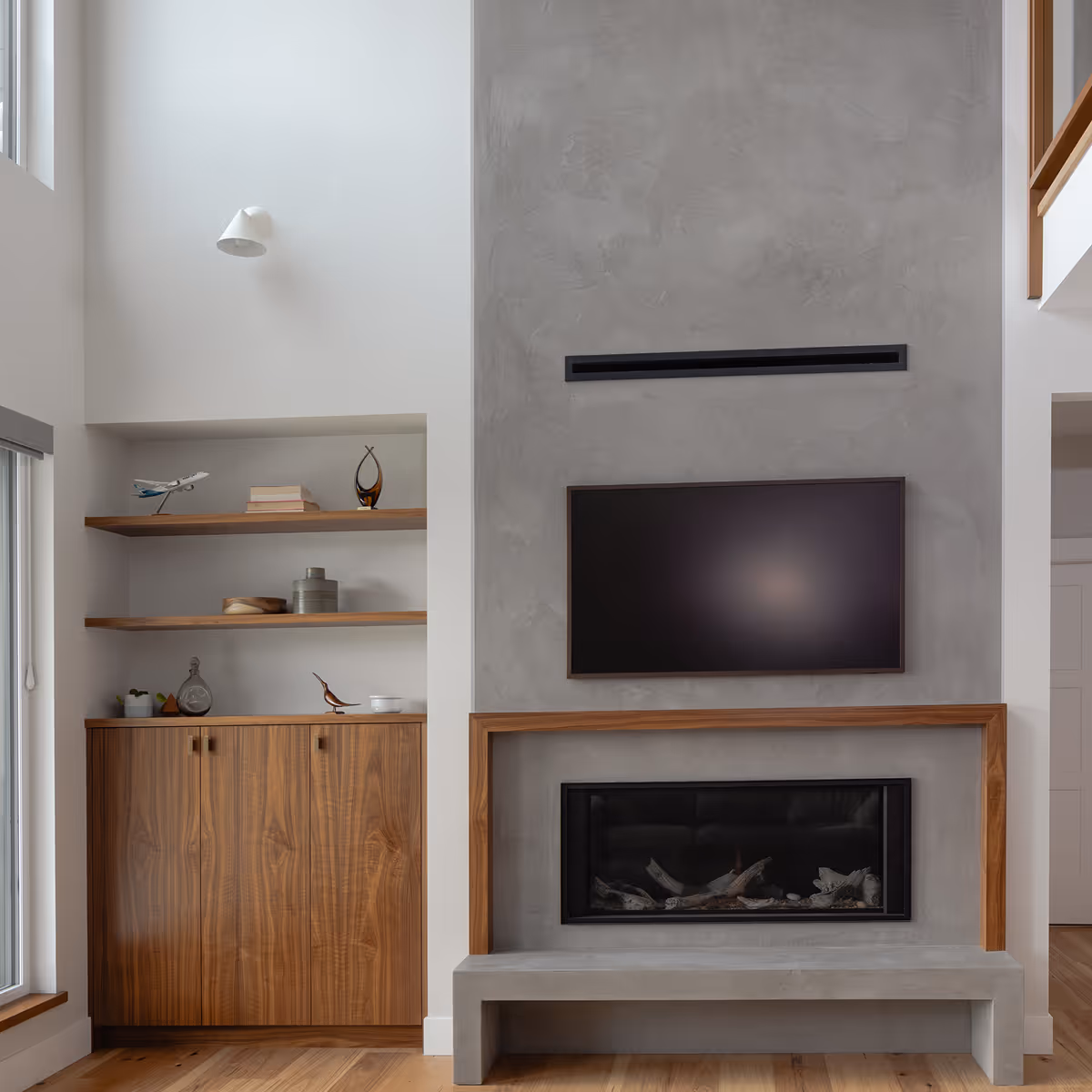 Custom micro-cement fireplace set into a soaring concrete wall in The Second Act living room